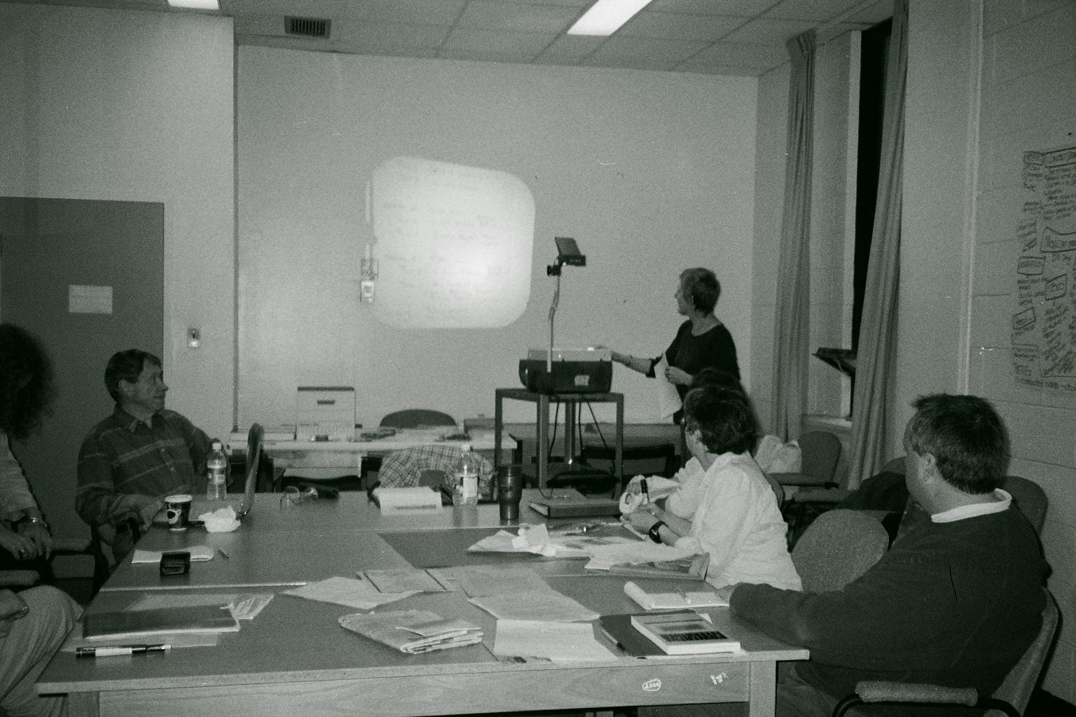 Mary Hamilton at overhead projector; participants seated around